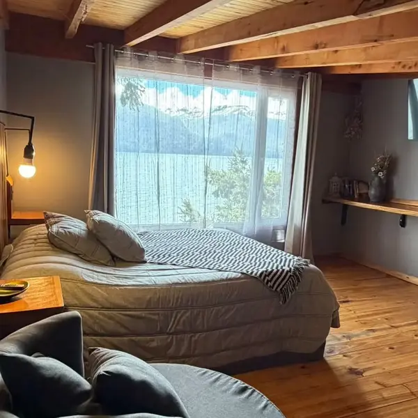 Dormitorio con sillón y ventana al lago